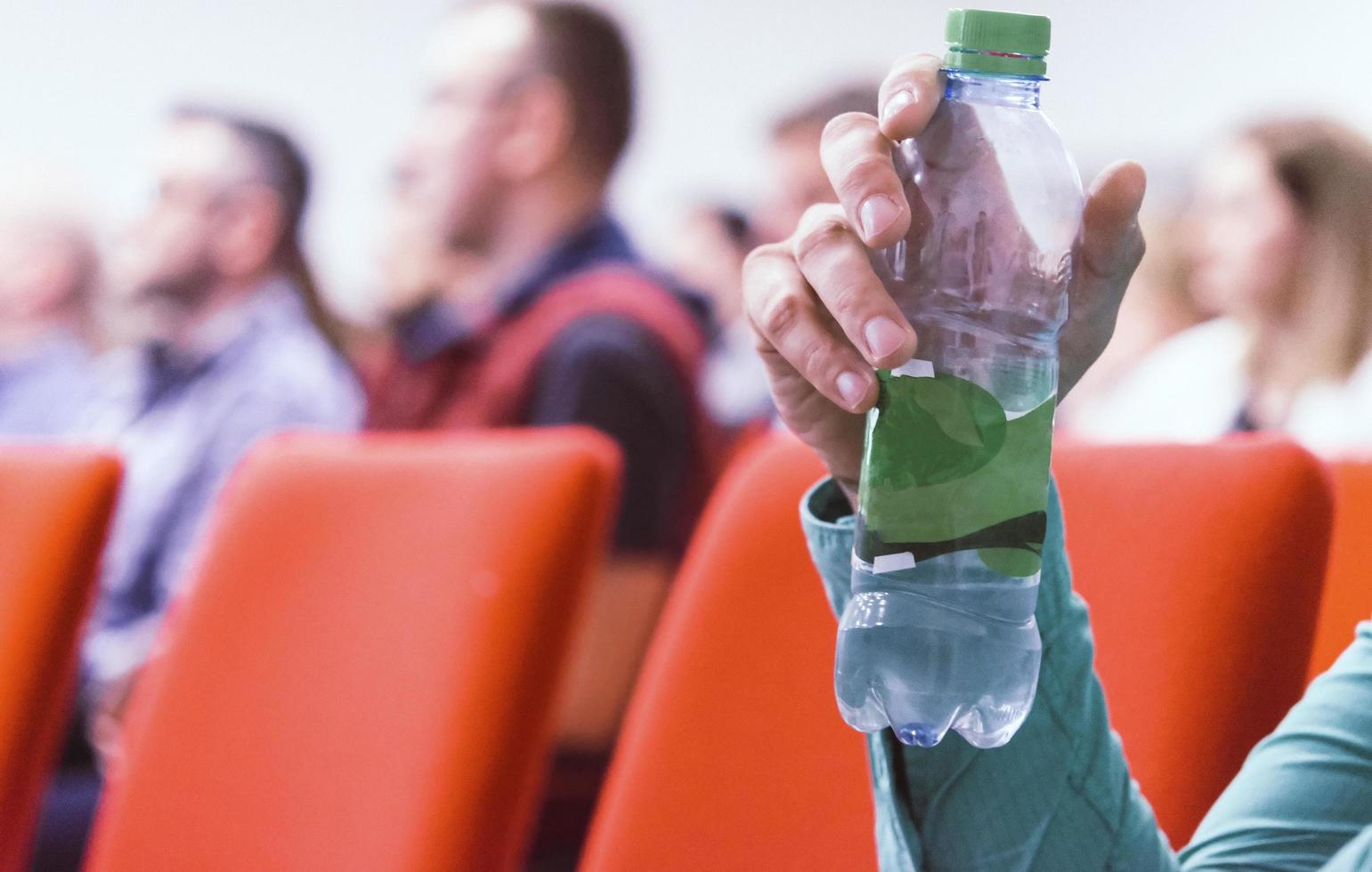 Business man on conference holding and drinking watter bottle. photo