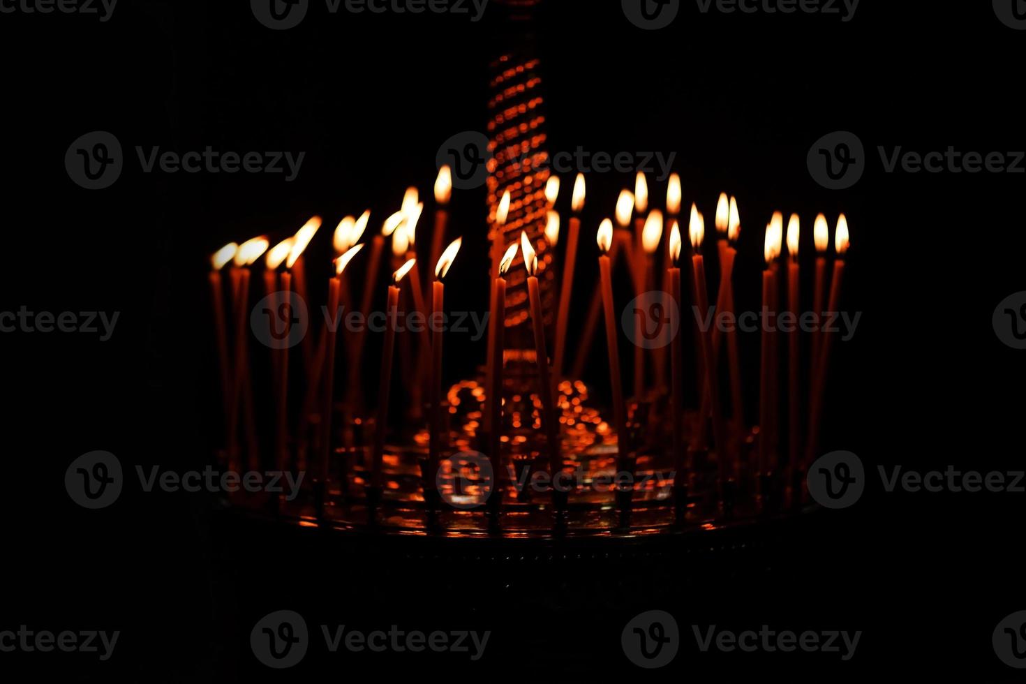 muchas velas encendidas por la noche sobre el fondo negro de la iglesia. conjunto de llama de vela aislado en fondo negro. grupo de velas encendidas en la oscuridad foto