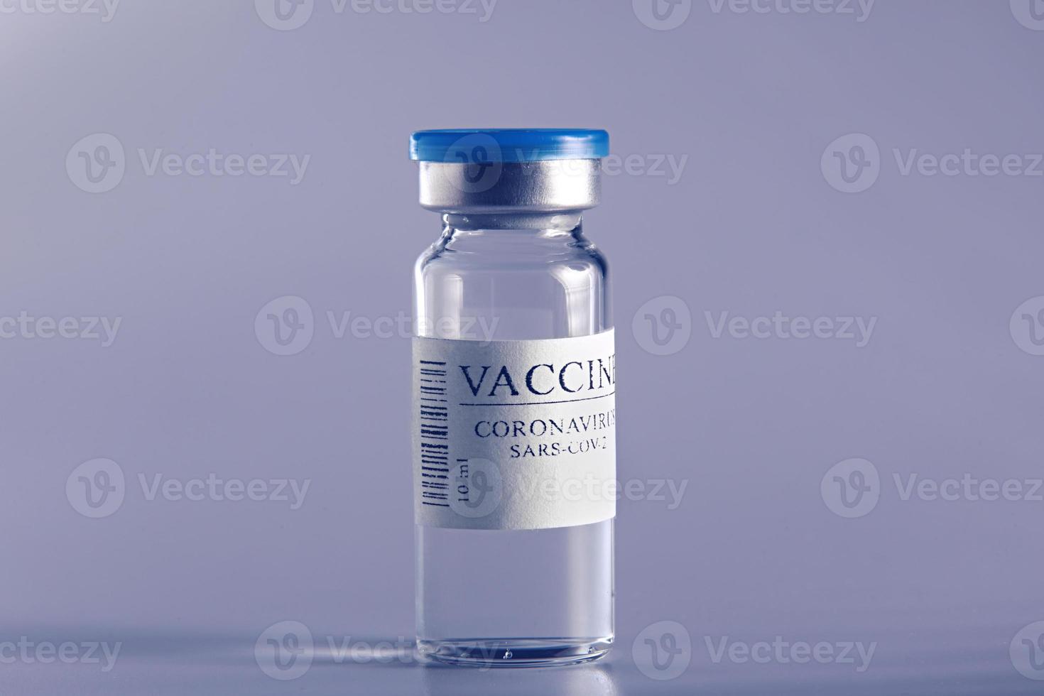 ampoule with Covid-19 vaccine in laboratory. to fight the coronavirus sars-cov-2 pandemic. Glass vial medical close-up isolated on a blue background. photo