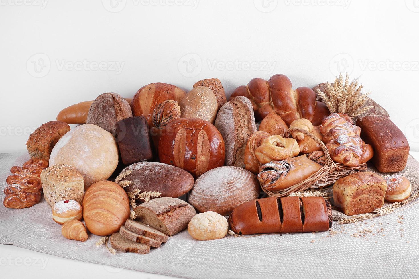 Different types of baked goods on linen and white wall background photo
