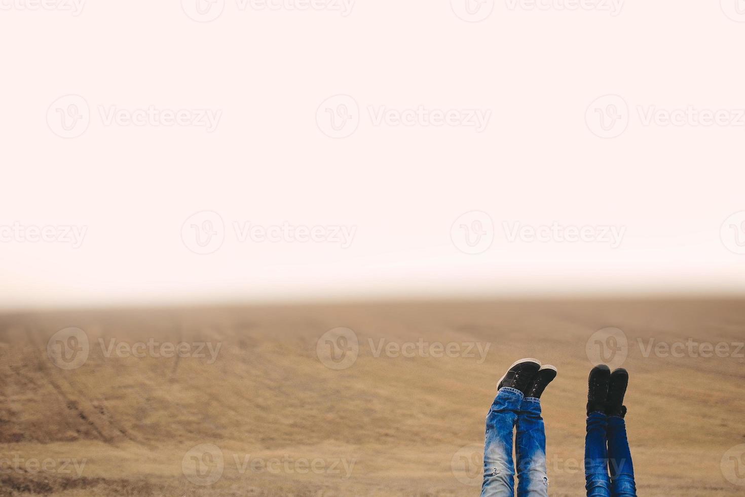 A women and man feet raised up high in the air. Shoot in field on autumn time. Place for inscription photo