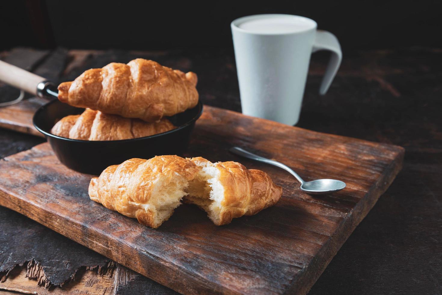 pan de desayuno, croissants y leche fresca en la mesa de madera. foto