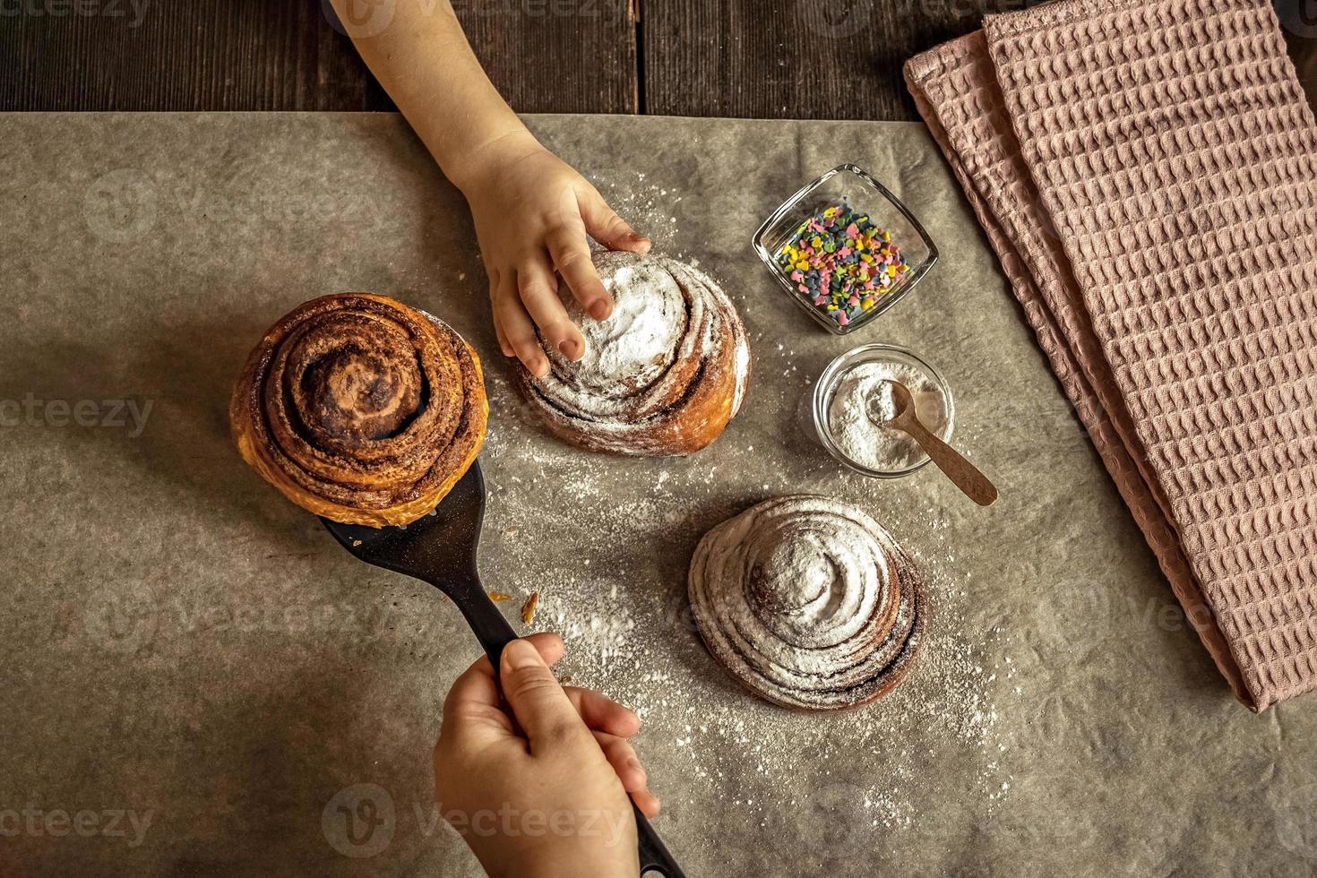 Children's hand takes a freshly baked cinnamon bun photo