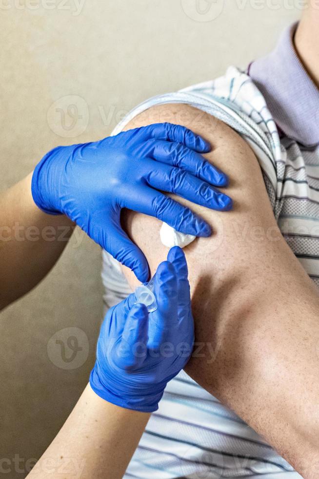 A doctor vaccinates a man against coronavirus at a clinic. Close-up. The concept of vaccination, immunization, prevention against Covid-19. photo