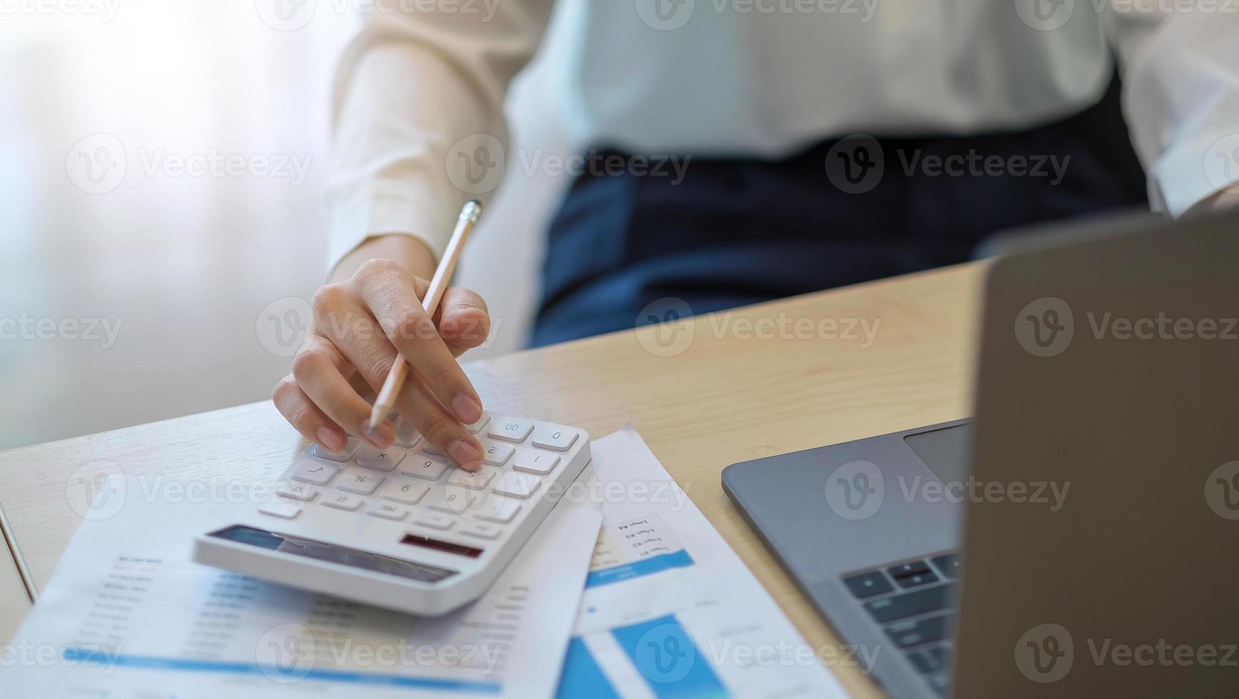 woman calculating individual income tax from financial document during note some data to sticky on window glass with calculator. photo