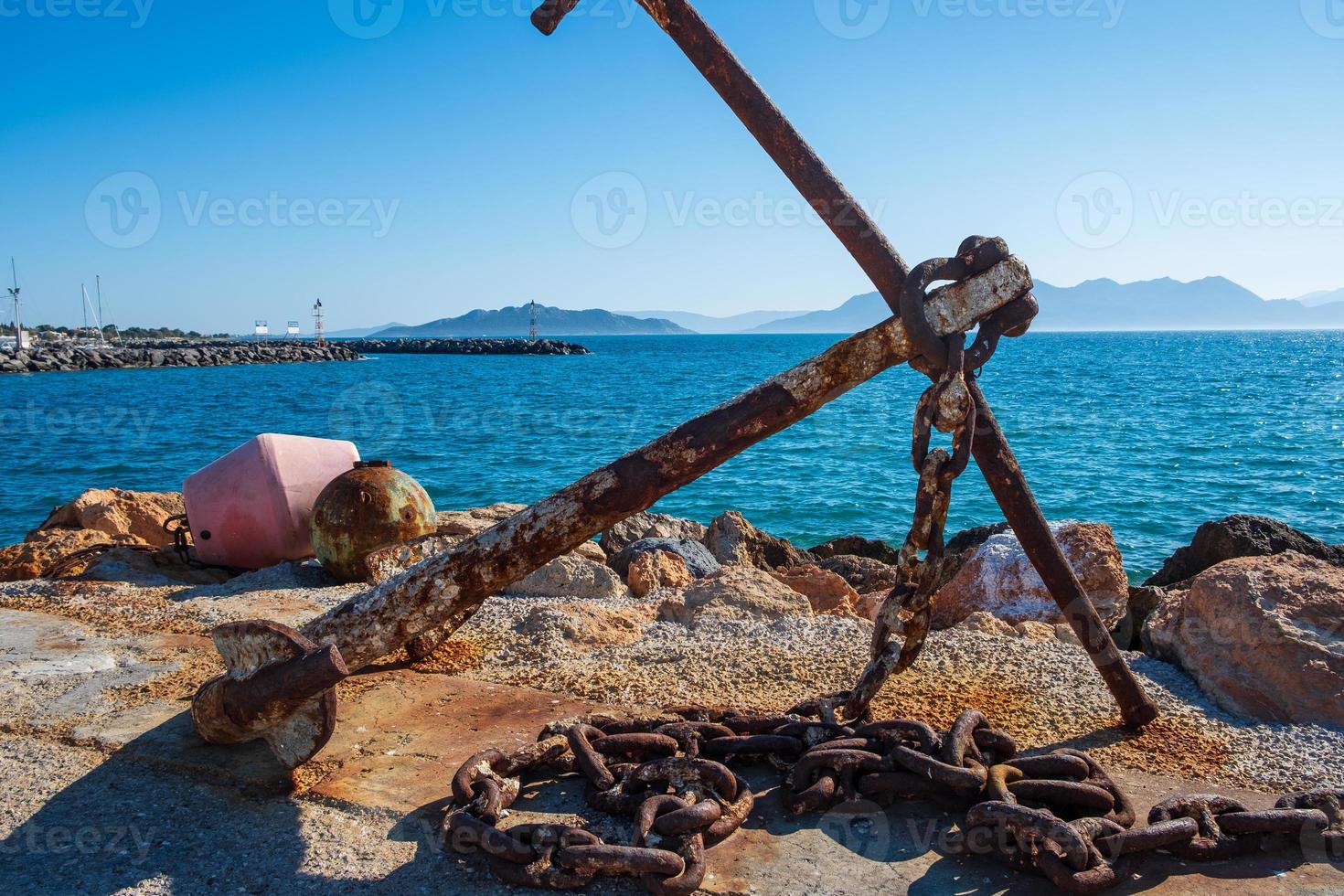 Rusty anchor on the shore at Aegina harbour in Greece photo