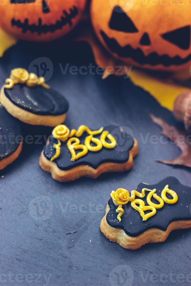Galletas de jengibre de halloween sobre fondo oscuro, con mini calabazas de halloween y decoración foto
