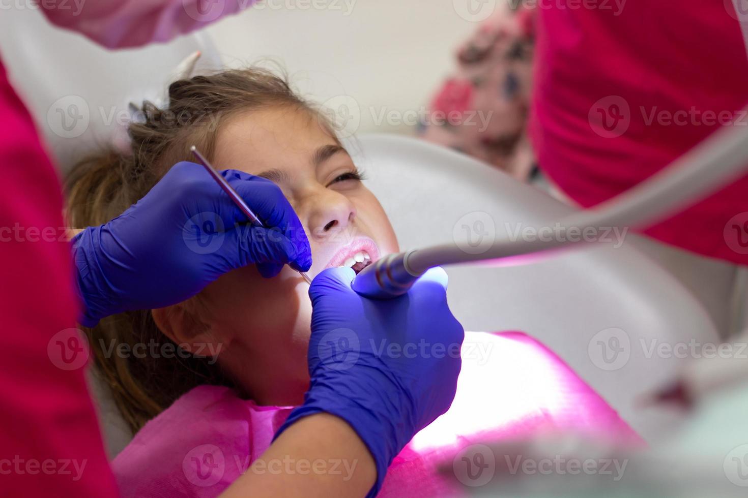 niña en la cita del dentista. Imagen sincera de la inspección y el diente que se está tratando. foto