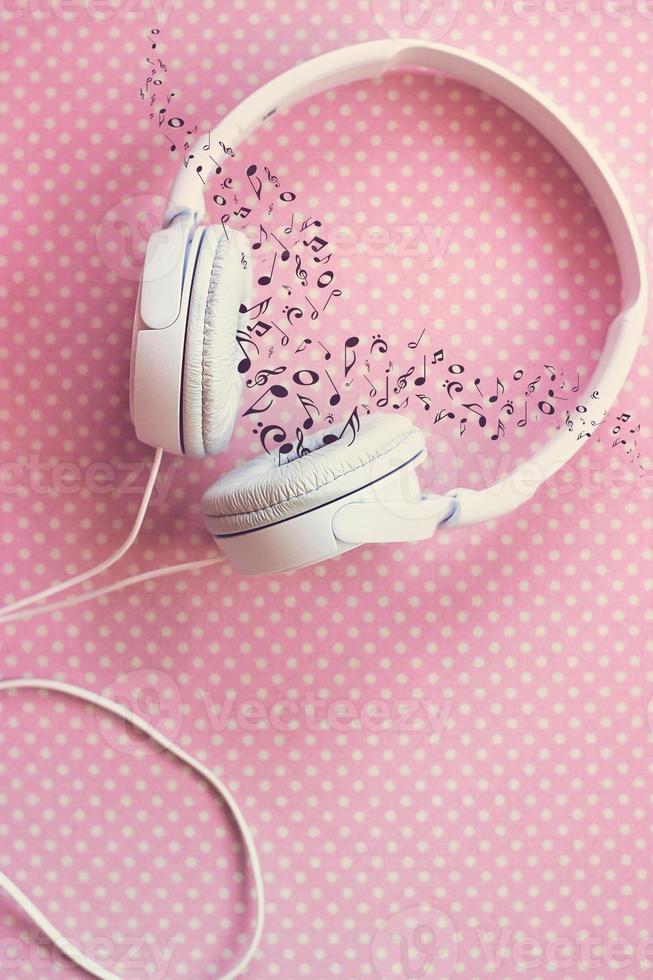 White headphones on pink background, with musical notes photo