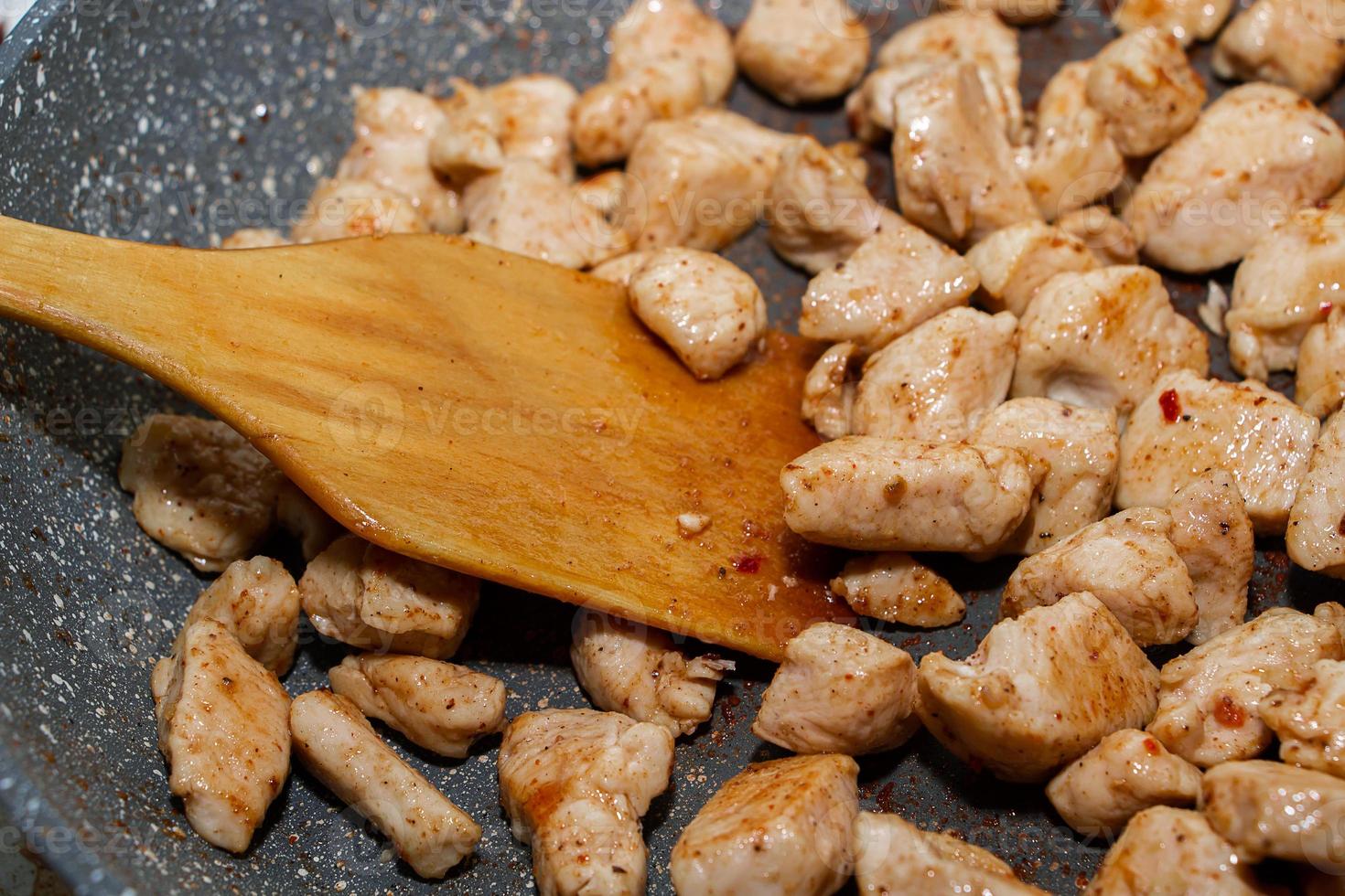 trozos de filete de pollo frito en una sartén. proceso de cocción. foto