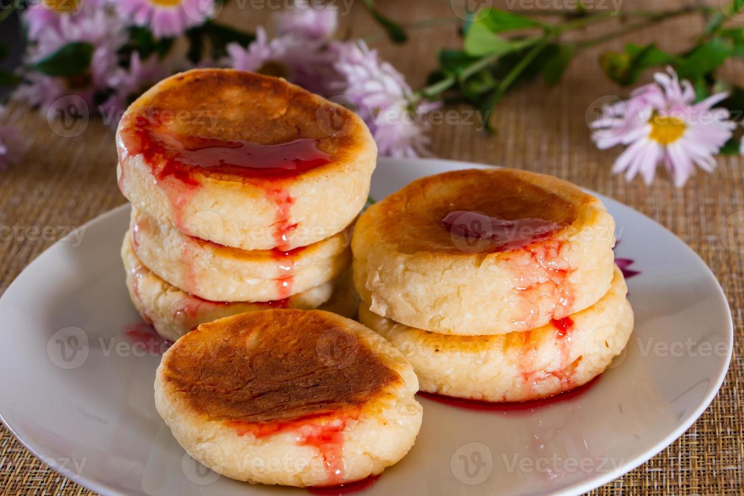Cheese pancakes with jam on a plate on a brown background. Breakfast food photo