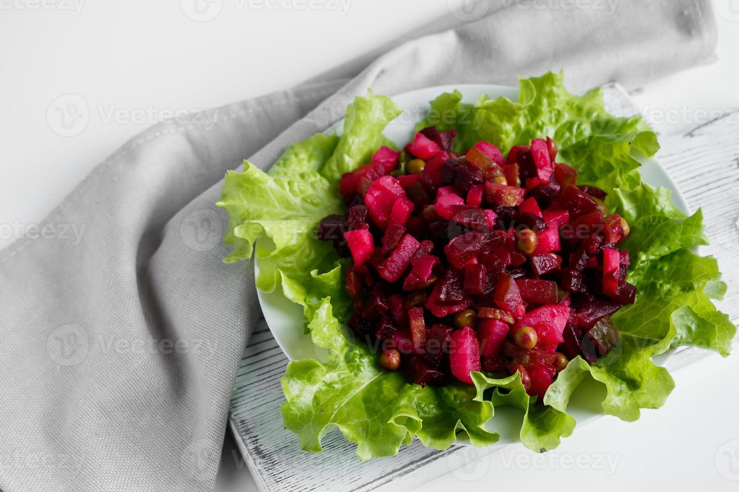 Russian salad vinaigrette on a gray background. Vegetarian dish with beets on a plate. photo