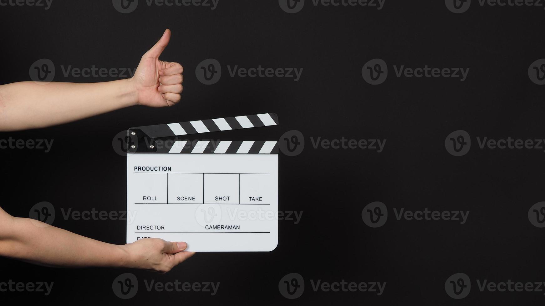 Hand holding a clapperboard and gives a like hand sign photo