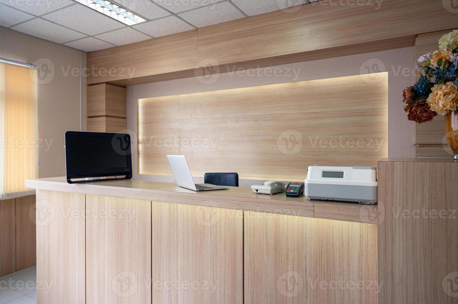 Modern wooden reception counter with monitor, laptop and electronic device in hospital photo
