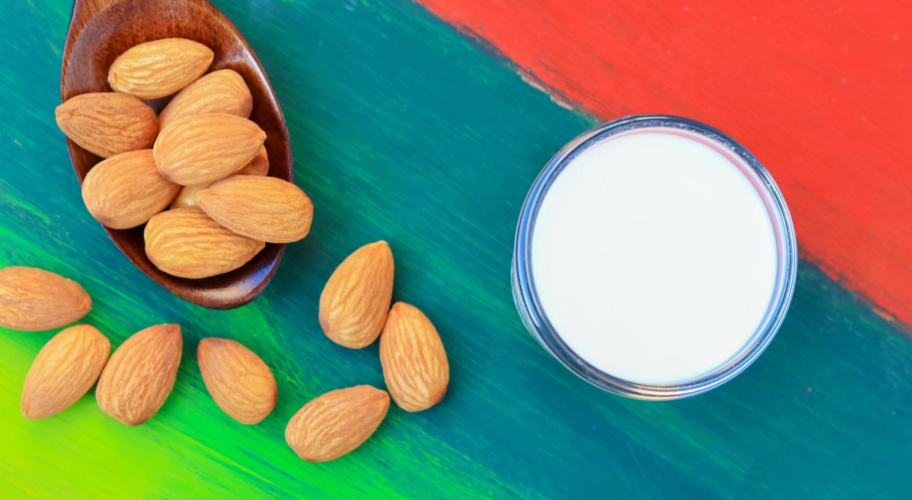 Almonds and milk in a glass on a beautiful colored natural wooden floor photo
