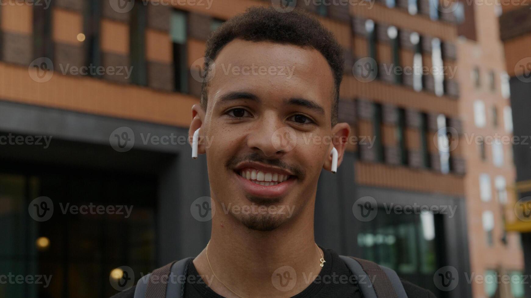 Portrait of young man wearing wireless ear pods laughing photo
