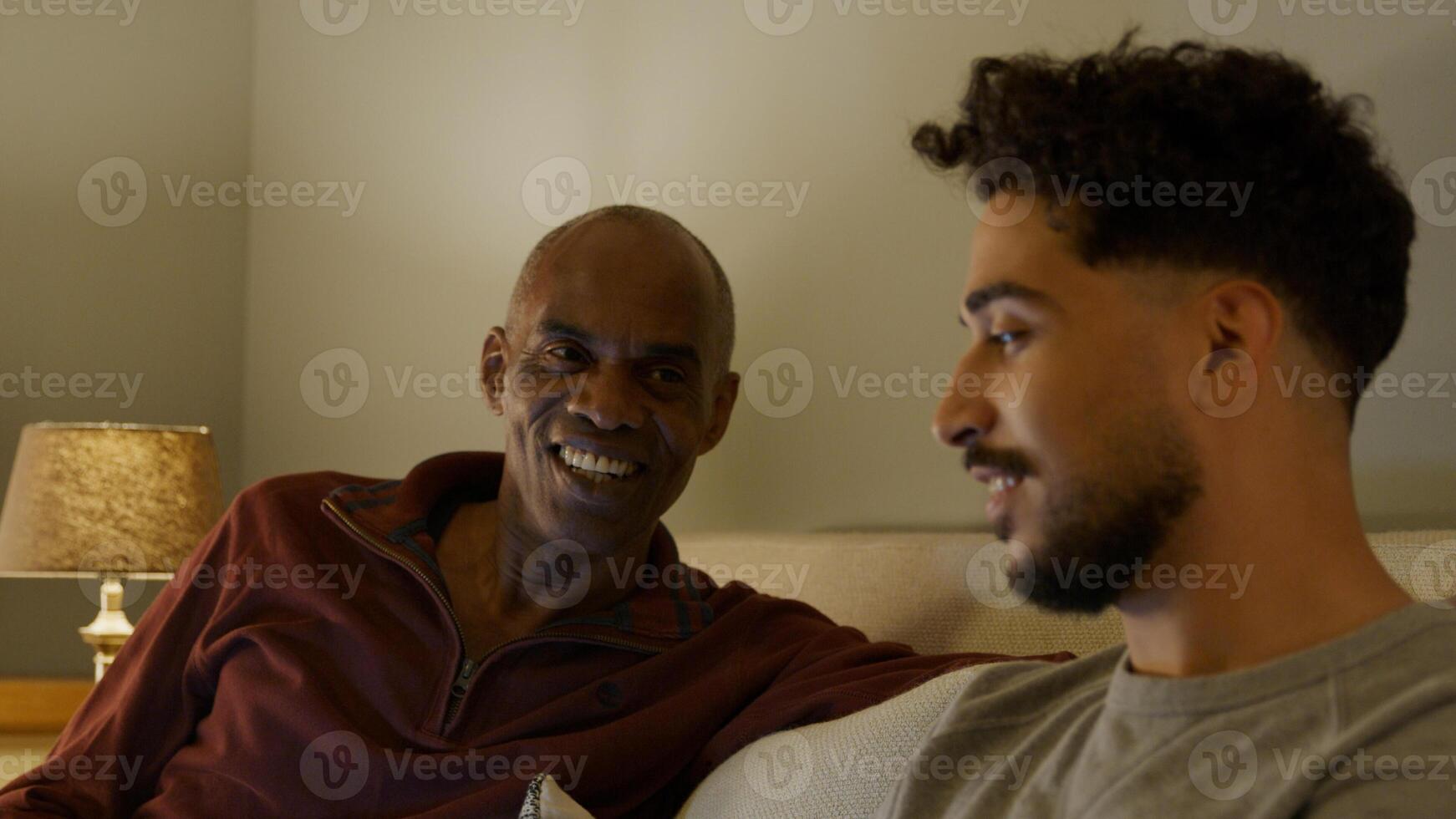 Mature man and young man relaxing on sofa at home photo