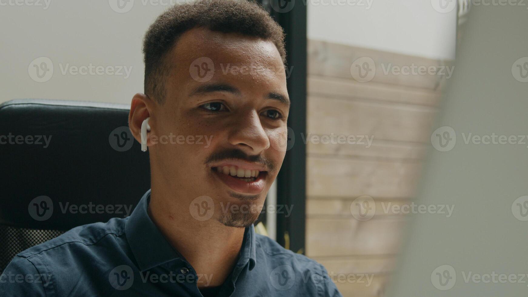 Young man wearing ear phones talking in online meeting photo