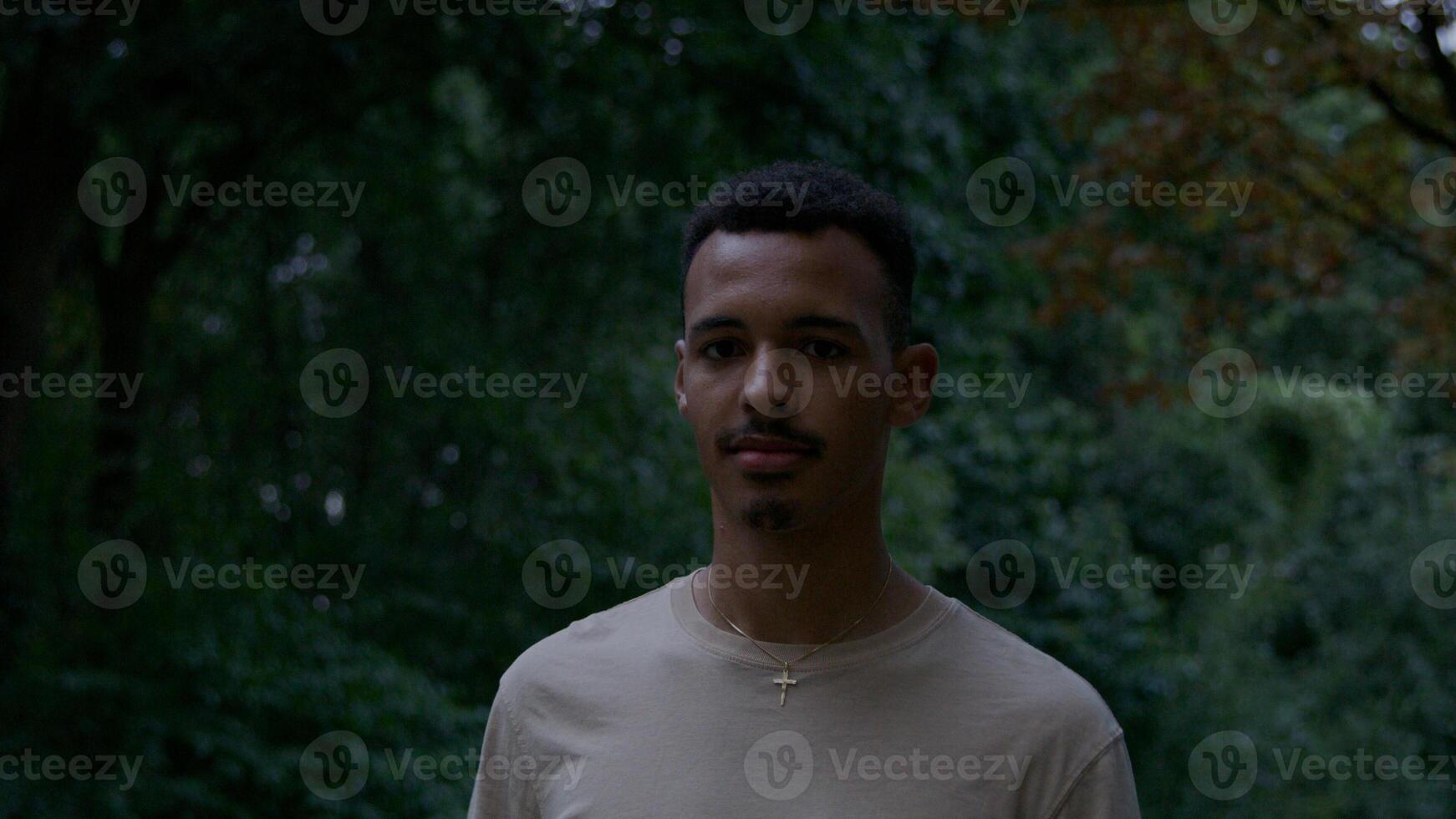 Portrait of young man walking in park looking at camera photo