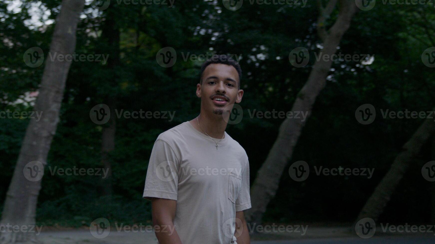 Portrait of young man walking in park looking at camera photo