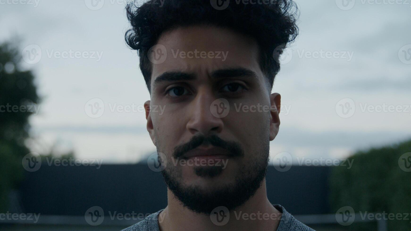 Young man with moustache and beard looking at camera photo