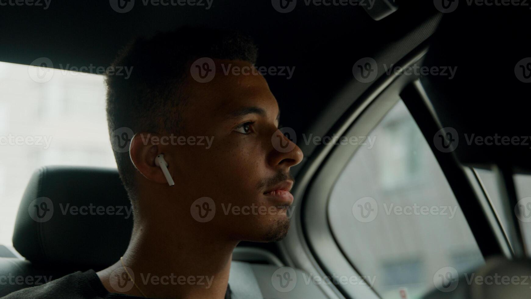 Young man sitting in back of cab putting ear phones in photo