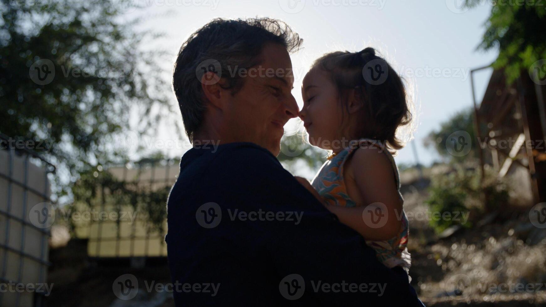 Portrait of father holding daughter in sunlight photo