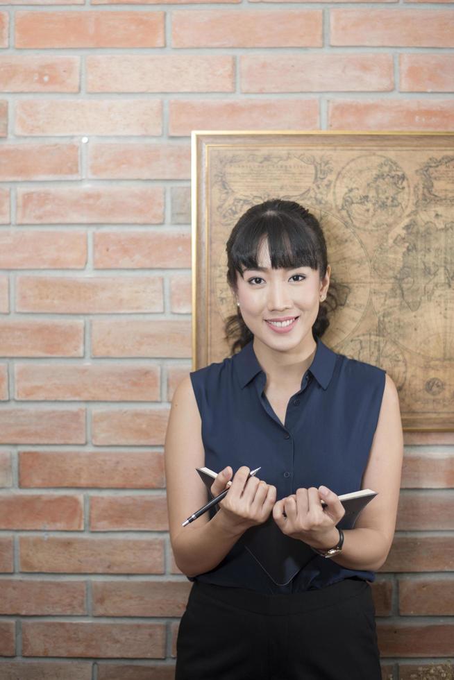 Attractive business woman smiling on brick wall photo