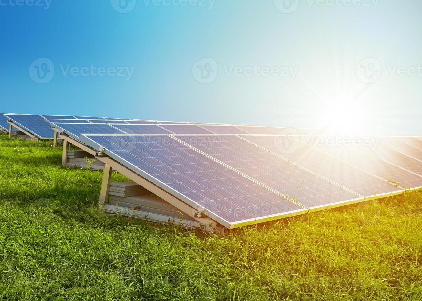 Paneles solares sobre hierba verde con sol. cielo azul de fondo. foto