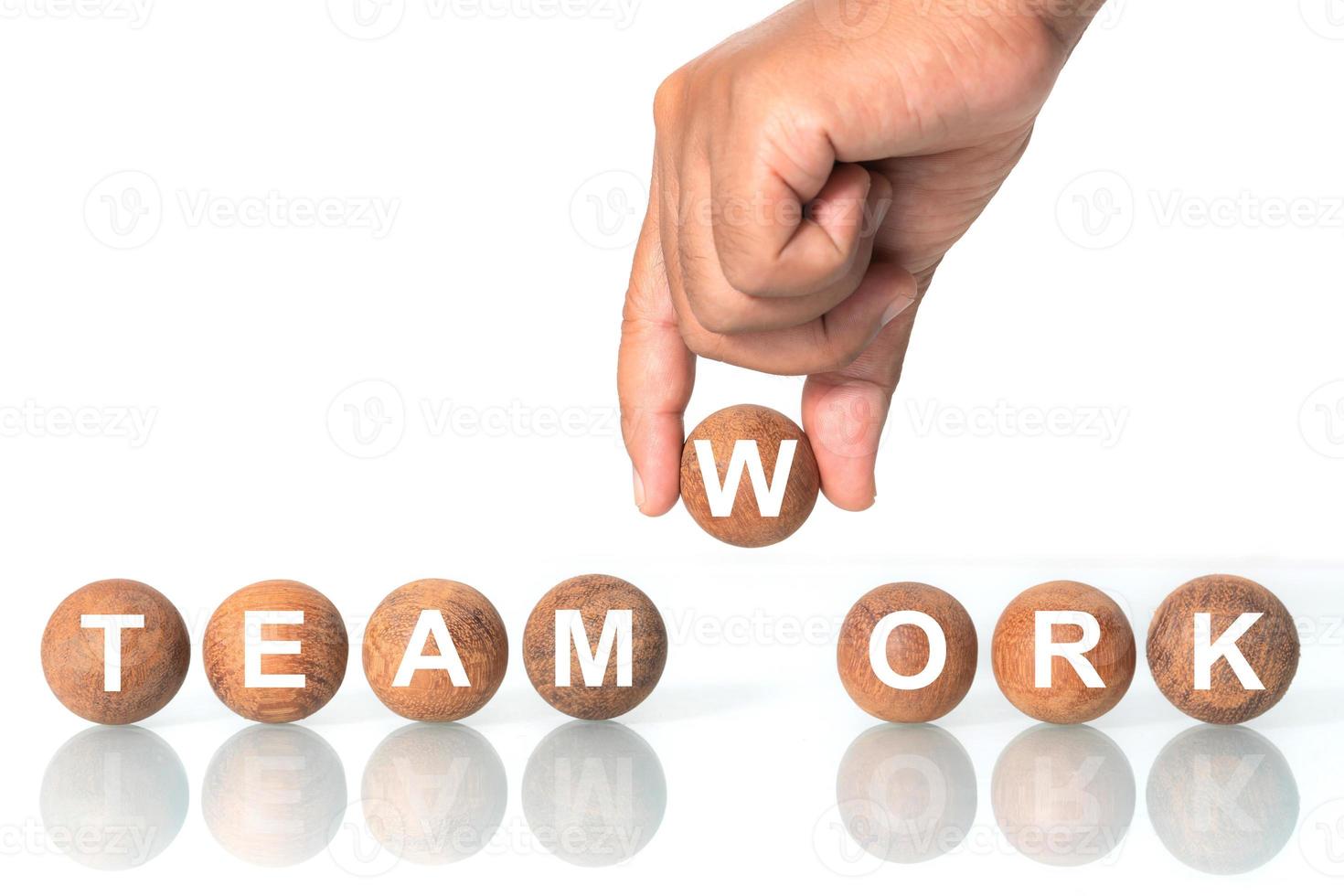 Hand putting on Wooden ball with word  TEAMWORK  The concept of teamwork bundles to victory photo