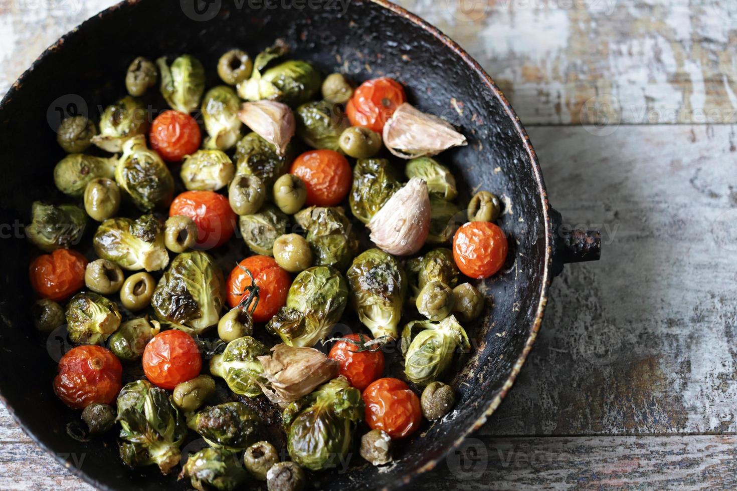 coles de Bruselas con verduras y hierbas en una sartén foto