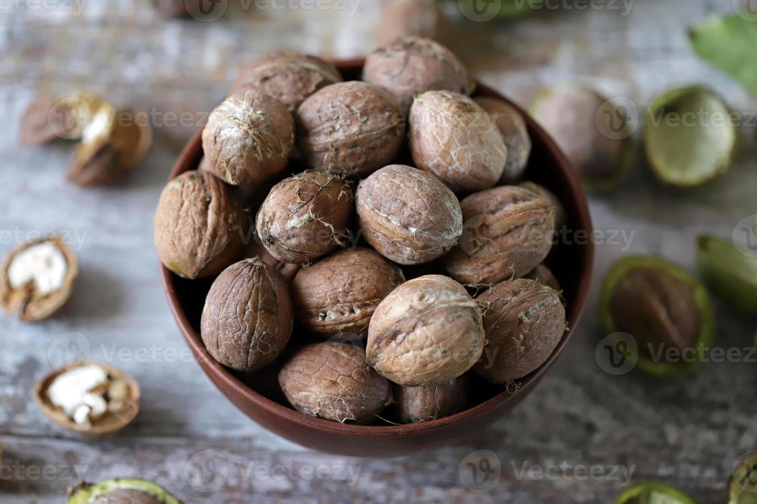 nueces en un bol. hojas de nuez nueces en una cáscara verde foto