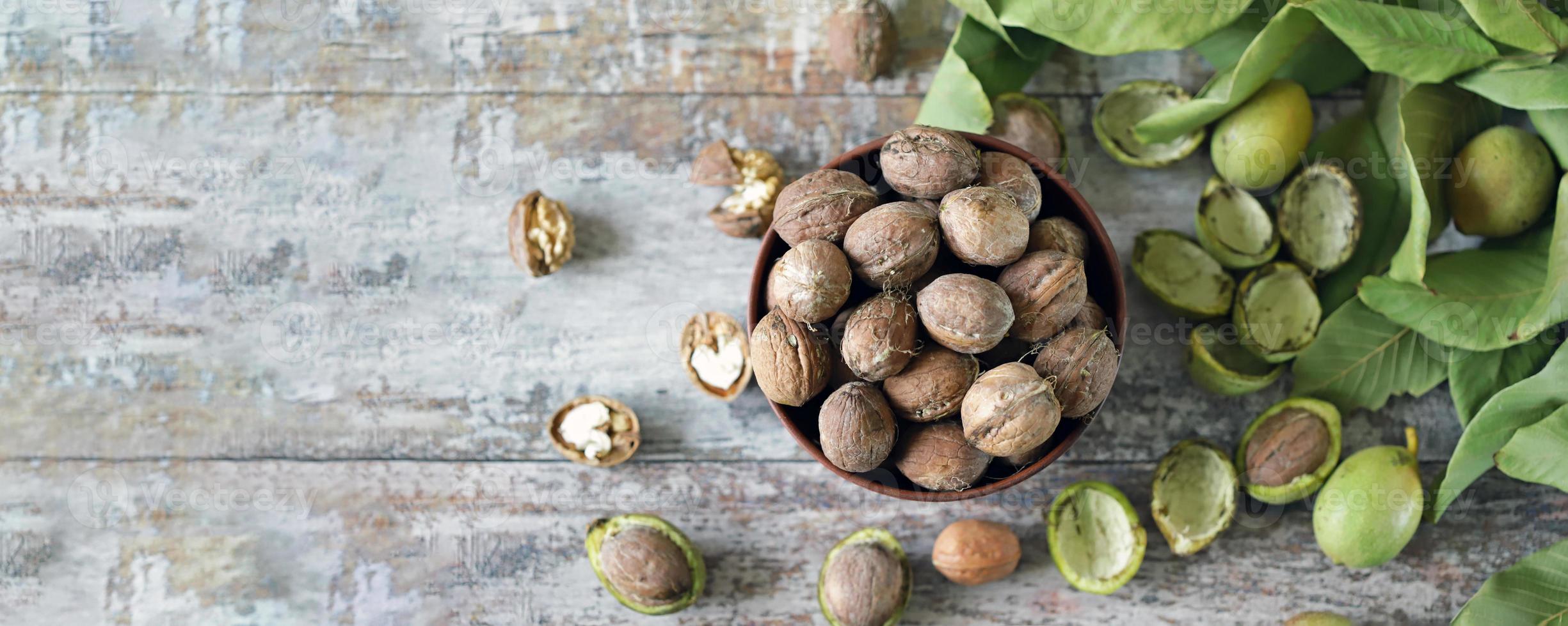 nueces en un bol. hojas de nuez nueces en una cáscara verde foto