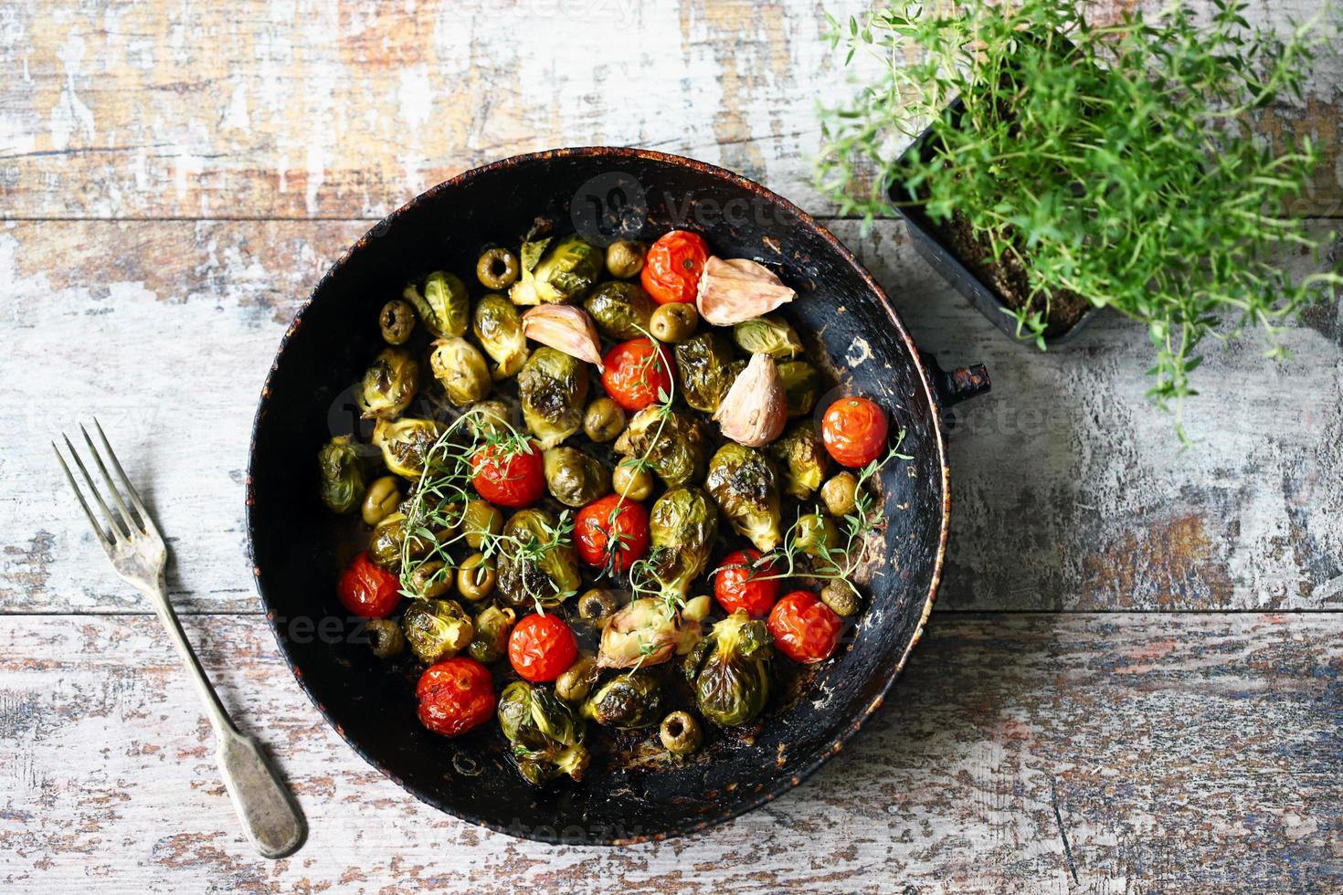 coles de Bruselas con verduras y hierbas en una sartén foto