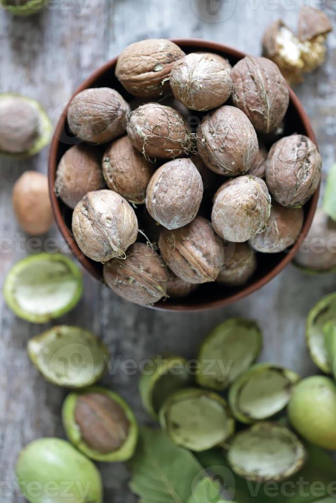 nueces en un bol. hojas de nuez nueces en una cáscara verde foto