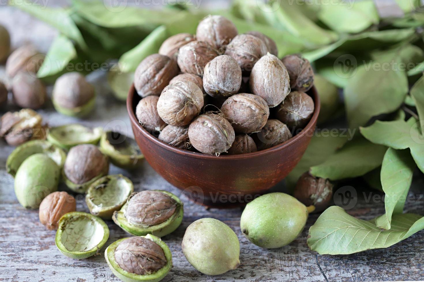 nueces en un bol. hojas de nuez nueces en una cáscara verde foto