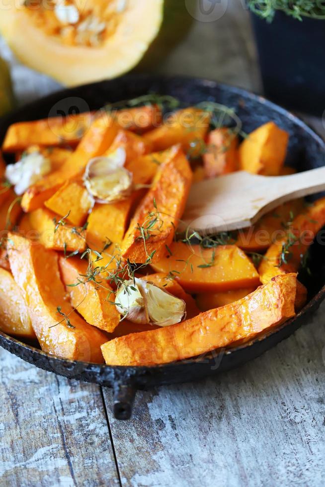 rodajas de calabaza al horno en una sartén con hierbas y ajo foto