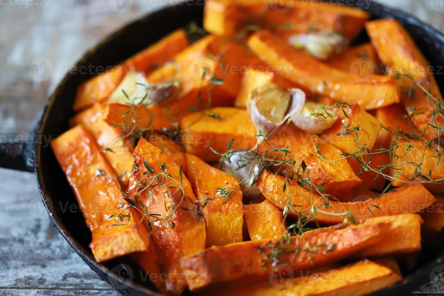 Baked pumpkin slices in a pan with herbs and garlic photo