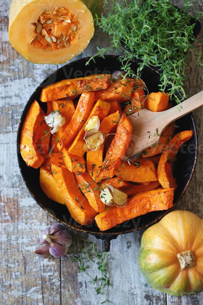 Baked pumpkin slices in a pan with herbs and garlic photo