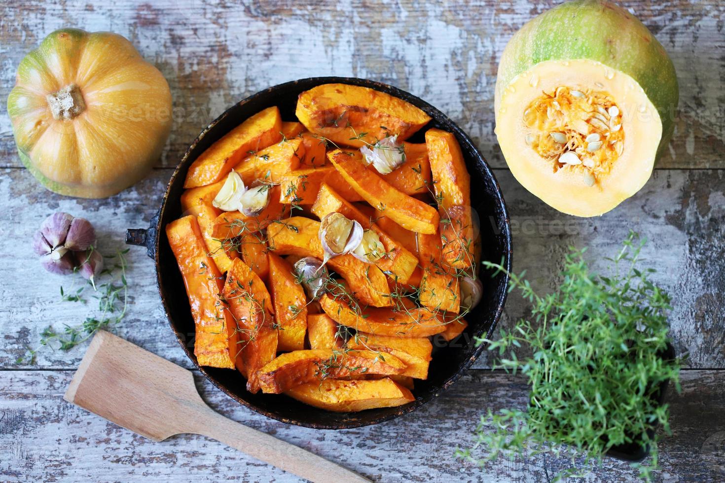 Baked pumpkin slices in a pan with herbs and garlic photo