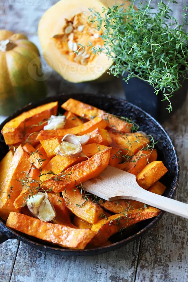 rodajas de calabaza al horno en una sartén con hierbas y ajo foto