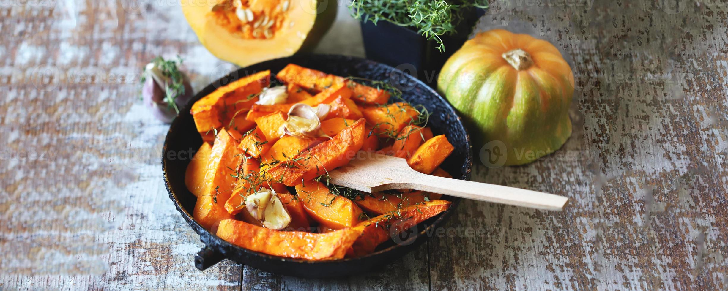 Baked pumpkin slices in a pan with herbs and garlic photo