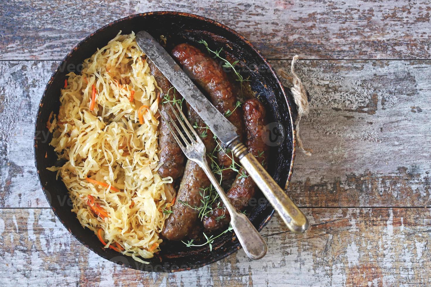 Bavarian sausages in a pan with stewed sauerkraut Oktoberfest food photo