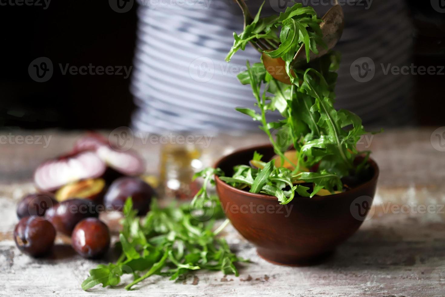 Ensalada saludable mezclar manos masculinas con cuchara y tenedor. ensalada de rúcula y ciruela. foto