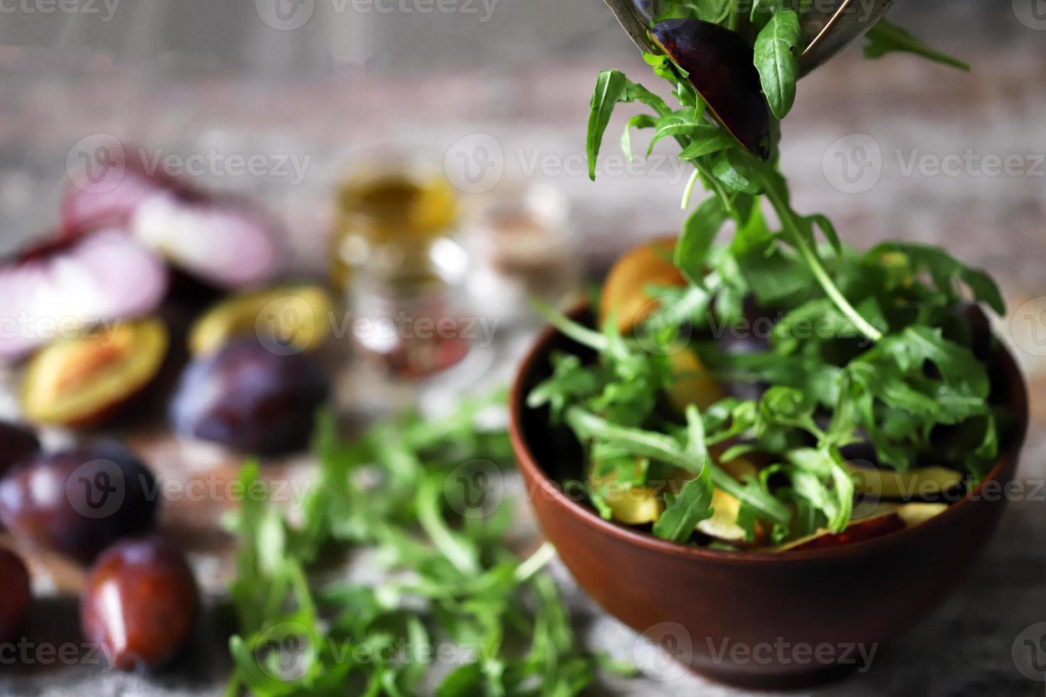 Ensalada saludable mezclar manos masculinas con cuchara y tenedor. ensalada de rúcula y ciruela. foto