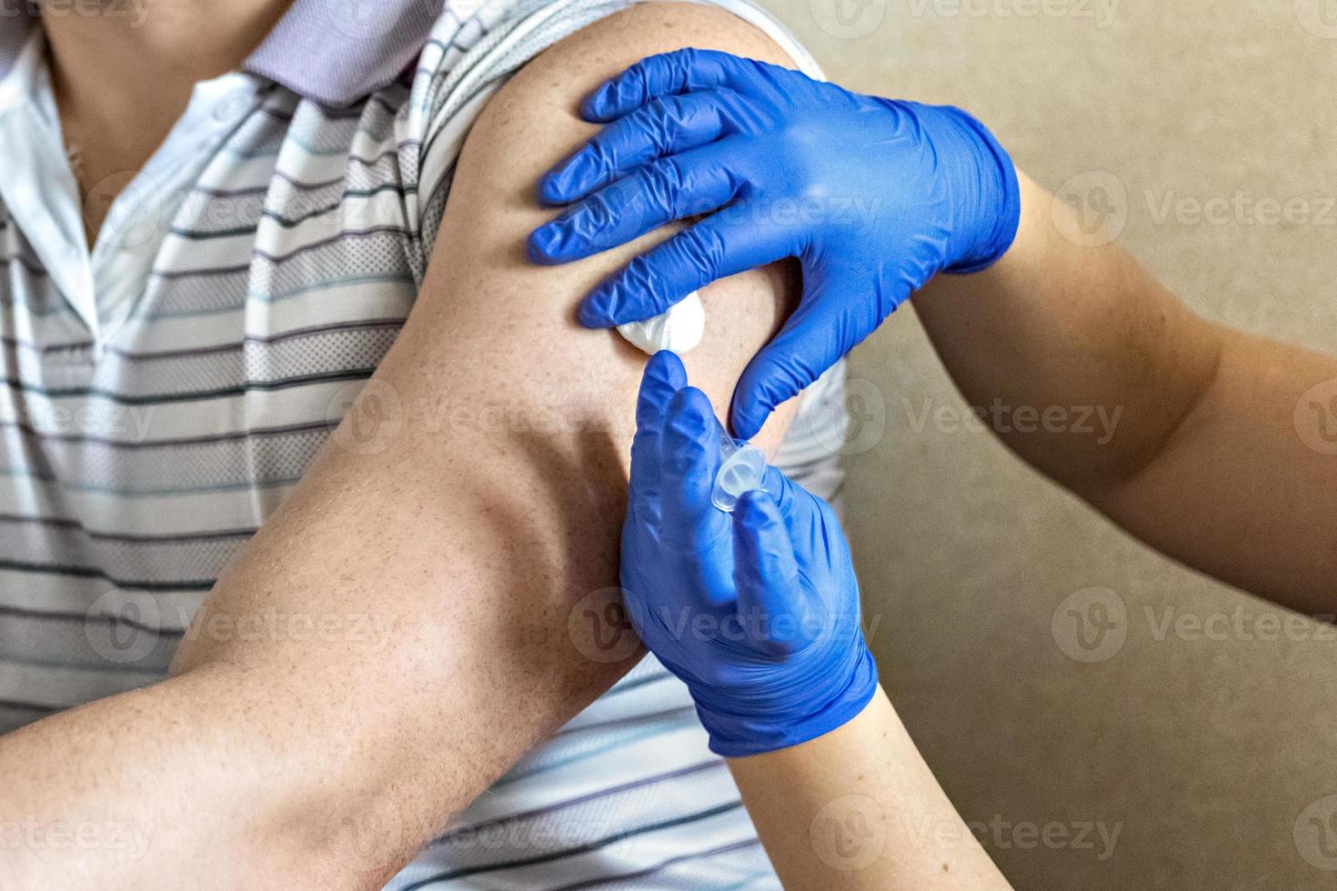 A doctor vaccinates a man against coronavirus at a clinic. Close-up. The concept of vaccination, immunization, prevention against Covid-19. photo