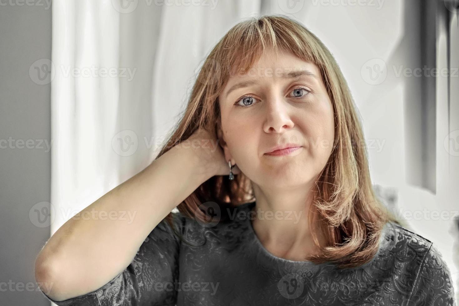 retrato de una mujer joven junto a la ventana en colores neutros foto