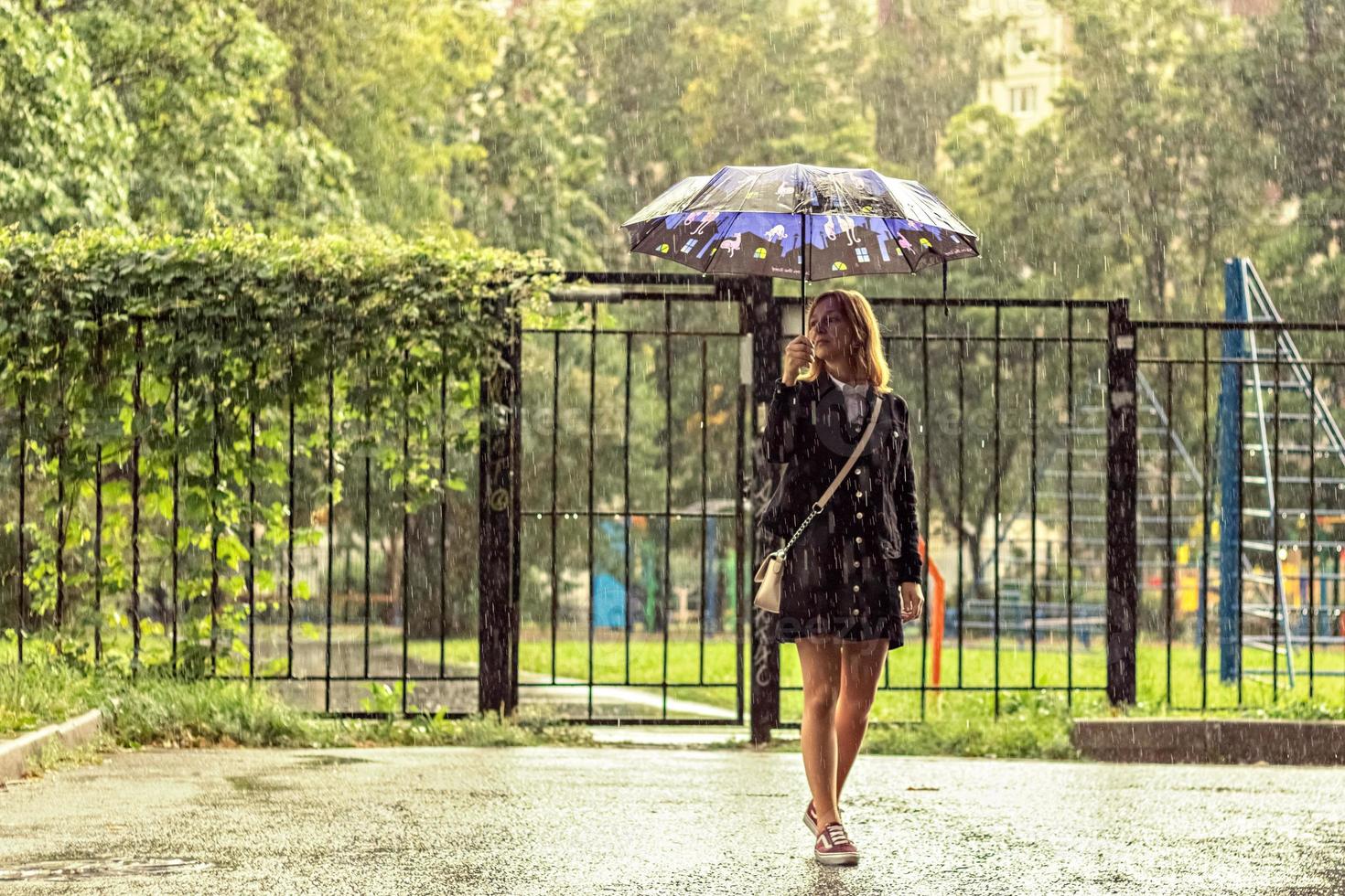 una mujer joven está en la calle bajo la lluvia bajo un paraguas. día lluvioso foto