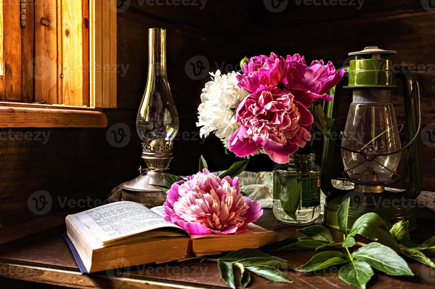 Bodegón de artículos vintage y un ramo de peonías en una mesa junto a la ventana en una antigua casa de pueblo. foto