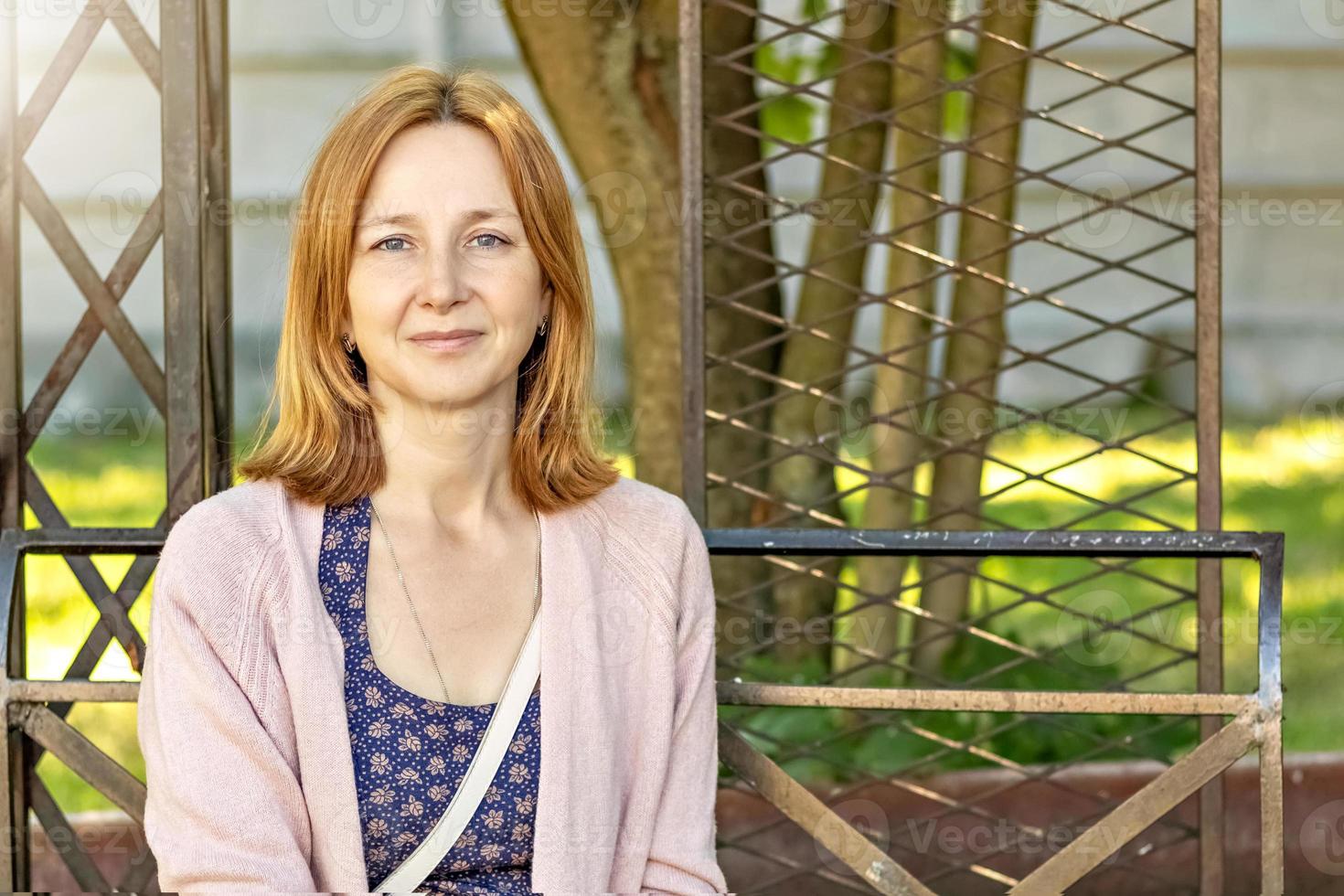 Young European woman sitting on a bench in the garden.Portrait of a smiling, happy girl photo